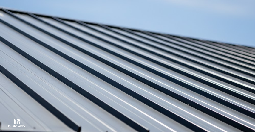 Close-up of a standing seam metal roof, showing smooth steel panels with raised seams running in parallel lines across the roof surface.